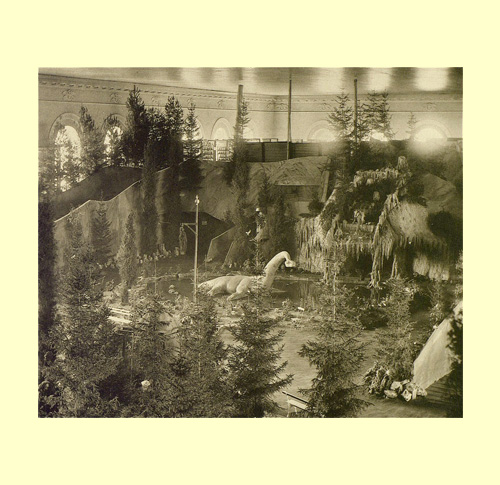 La foto restituisce assieme al primo piano del plesiosauro una veduta allargata e dall’alto dell’area della sezione paletnologica nella quale è collocato il rettile acquatico del triassico. Da questa prospettiva ben si apprezza la complessità del percorso che conduce dinnanzi all’enorme creatura ma pure prosegue prendendo altre strade che costeggiano in alto la conca con l’acquitrino e la grotta, ricavandosi ulteriori spazi espositivi. foto 1